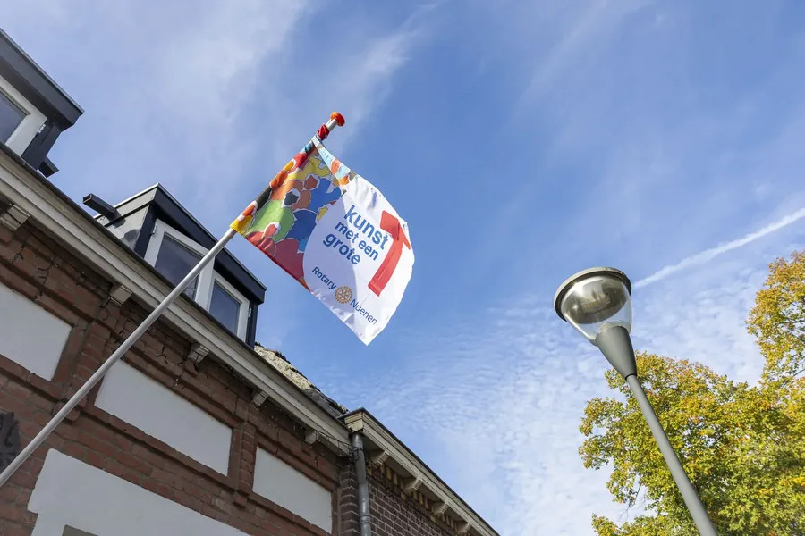 De vlag van KunsT met een grote T aan een gevel in Nuenen, september 2026