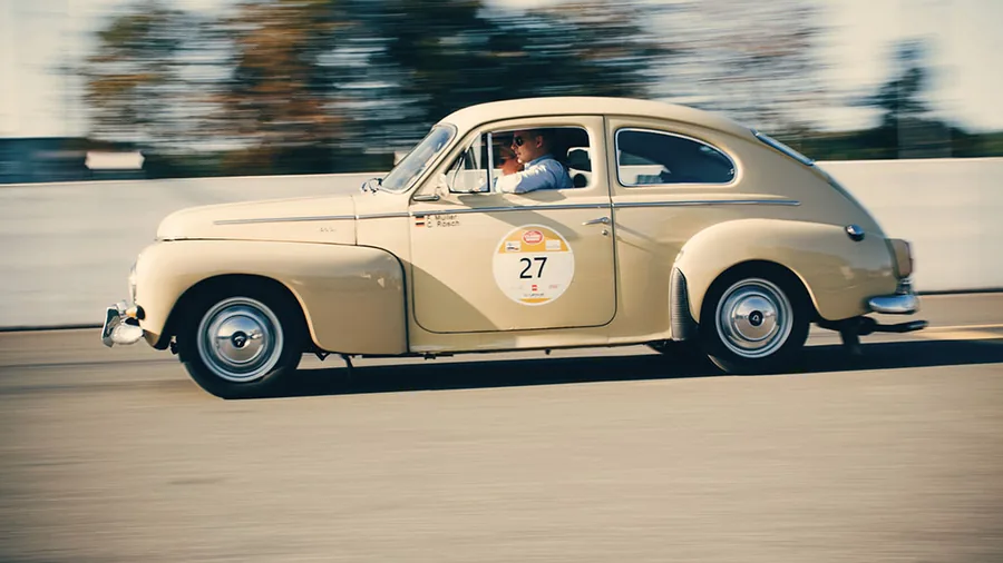 Klassieke auto met rallyschild in volle vaart